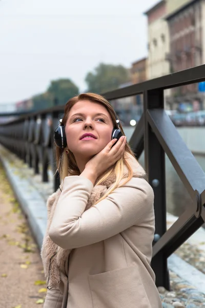 Hermosa chica escuchando música con auriculares en un co urbano — Foto de Stock