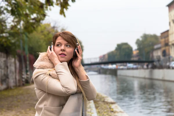 Beautiful girl listening to music with headphones in an urban co — Stock Photo, Image