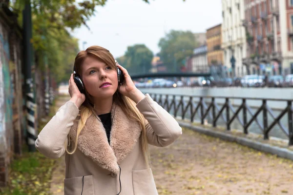 Belle fille écoutant de la musique avec des écouteurs dans une co urbaine — Photo