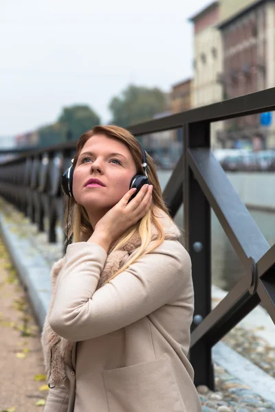 Девушка слушает музыку в наушниках в городском кафе — стоковое фото