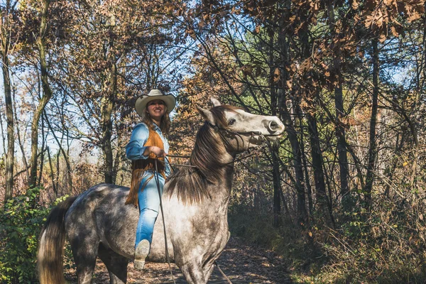 Красивая девушка верхом на серой лошади — стоковое фото