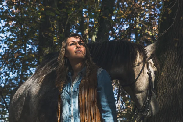 Pretty girl standing by her grey horse — Stock Photo, Image
