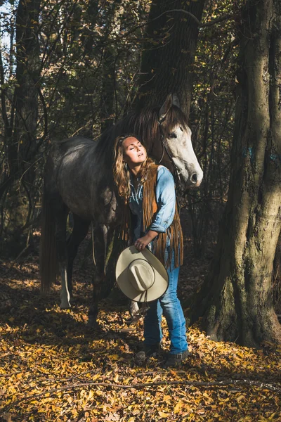 Красивая девушка, стоящая у серого коня — стоковое фото