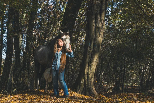 Pretty girl standing by her grey horse — Stock Photo, Image