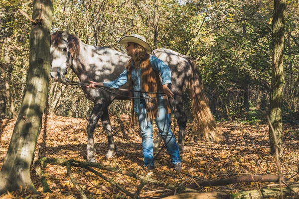 Красивая девушка, стоящая у серого коня — стоковое фото