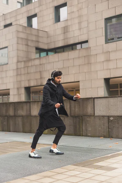 Hombre indio guapo escuchando música en un contexto urbano —  Fotos de Stock