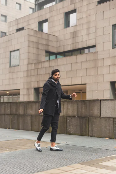 Hombre indio guapo escuchando música en un contexto urbano —  Fotos de Stock