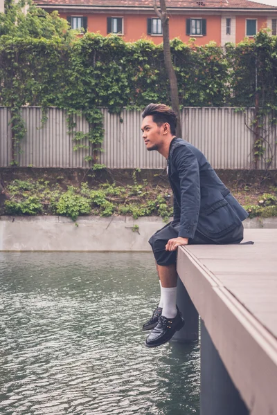 Handsome Asian model posing by an artificial basin — Stock Photo, Image