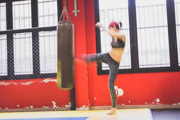 Beautiful girl boxing against punching bag (intentionally blurred) — Stock Photo, Image