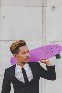 Genç yakışıklı Asya model kaykayıyla poz