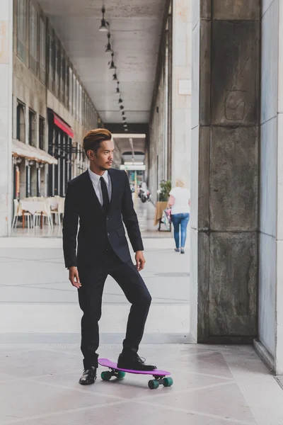 Young handsome Asian model posing with his skateboard — Stock Photo, Image