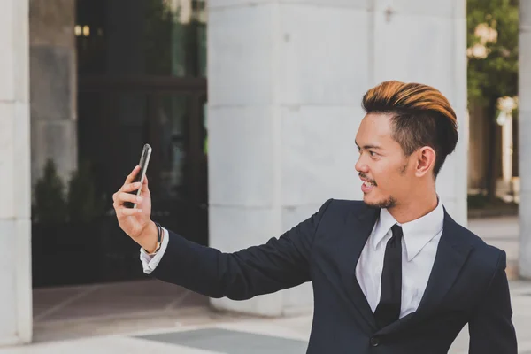 Young handsome Asian model taking a selfie in the city streets — Stock Photo, Image