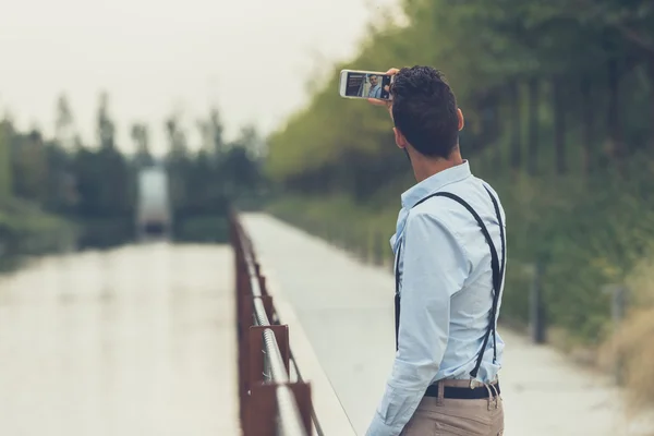 Jonge knappe man met een selfie door een rivier — Stockfoto
