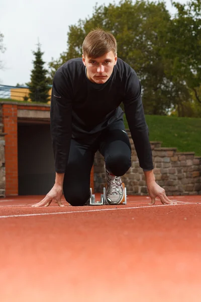 Portret van sexy muscle man in lage start op stadion — Stockfoto