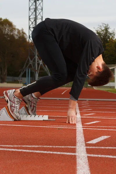 Portret van sexy muscle man in lage start op stadion — Stockfoto