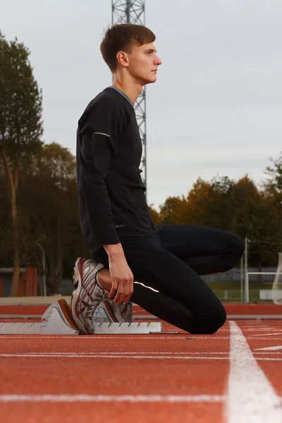 Portrét sexy svalů člověka v nízký start na stadionu — Stock fotografie