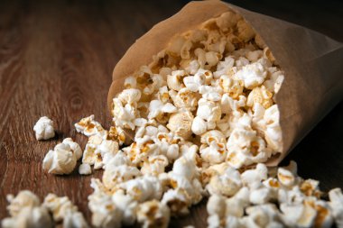 ahşap bir masa üzerinde bir kağıt torba tuzlu popcorn