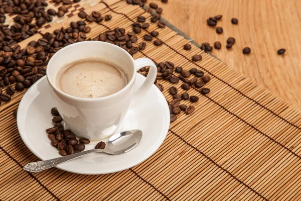 コーヒー豆と竹のナプキンに泡の香りのコーヒーカップ — ストック写真