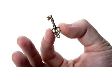 Beyaz arka planda sihirli bir anahtar tutan adamın eli.