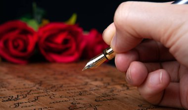 Dolma kalem elinde. Yazılı ve kırmızı gül yakın.