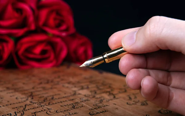 Πένα Στυλό Στο Χέρι Στο Γράμμα Κείμενο Και Κόκκινα Τριαντάφυλλα — Φωτογραφία Αρχείου