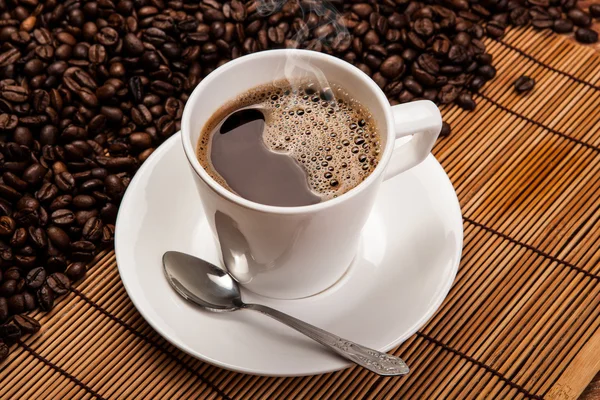 Taza de café negro con granos de café tostados — Foto de Stock