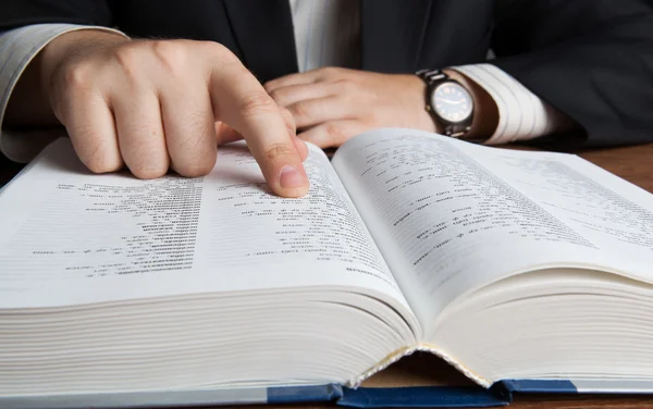 Man looking in the large dictionary — Stock Photo, Image