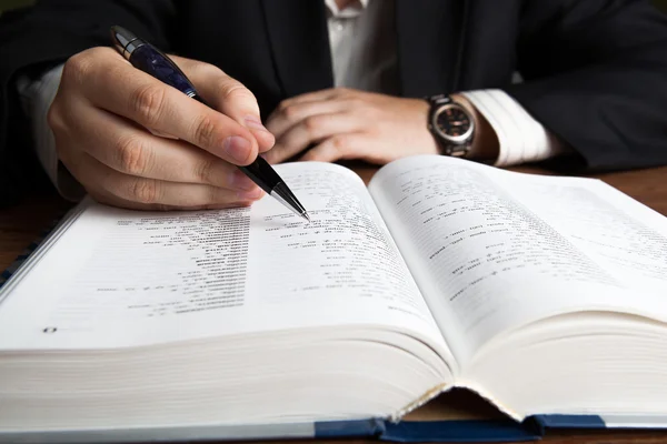 Man looking in the large dictionary — Stock Photo, Image