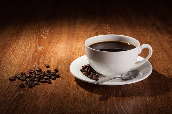 Bodegón con una taza de café negro y granos de café tostados — Foto de Stock