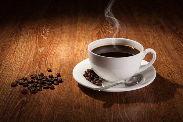 Bodegón con una taza de café negro y granos de café tostados — Foto de Stock