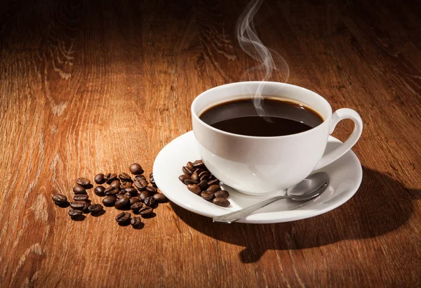 Bodegón con una taza de café negro y granos de café tostados —  Fotos de Stock