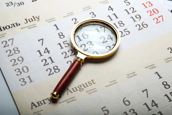 Vergrootglas liggend op de kalender — Stockfoto