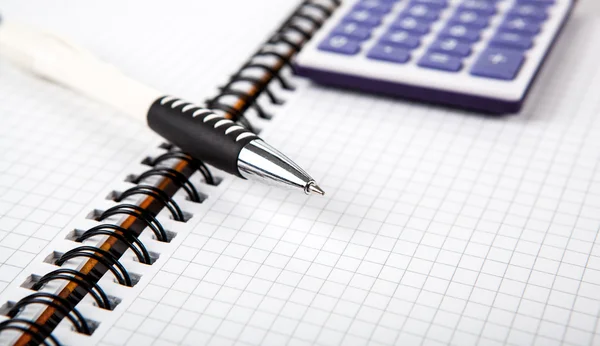 Caneta em um notebook em uma célula e calculadora — Fotografia de Stock