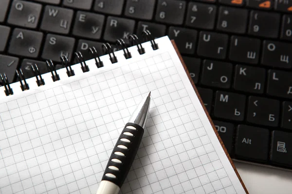 Stift auf einem Notizbuch in eine Zelle und Tastatur — Stockfoto
