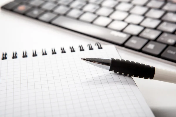 Caneta em um notebook em uma célula e teclado — Fotografia de Stock