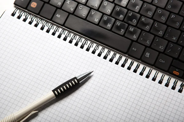 Caneta em um notebook em uma célula e teclado — Fotografia de Stock