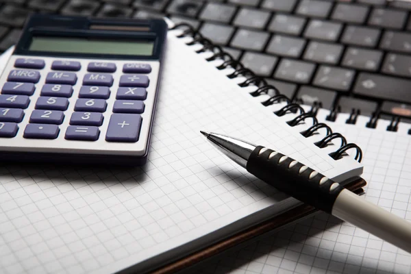 Pen met calculator op een laptop en een toetsenbord — Stockfoto