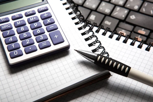 Pen with calculator on a notebook and keyboard — Stock Photo, Image