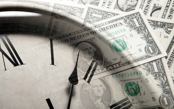 Часы на фоне банкнот долларов — стоковое фото
