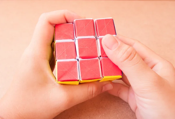 Spelen puzzel rubik kubus maken door papier in han — Stockfoto