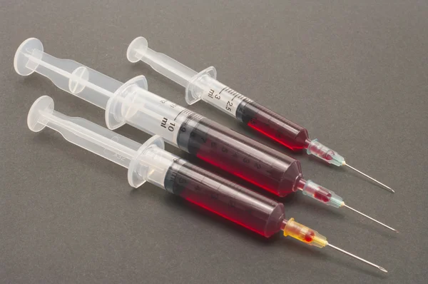 Syringe met bloed geïsoleerd op grijze achtergrond — Stockfoto