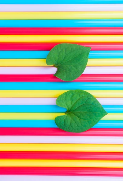 Foglie a forma di cuore su sfondo di cannucce colorate — Foto Stock