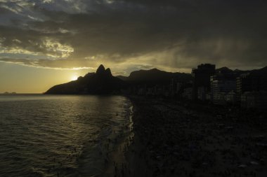 Rio de Janeiro Brezilya 'da Ipanema sahilinde günbatımının insansız hava aracı görüntüsü. Arka planda Dois Irmaos var.