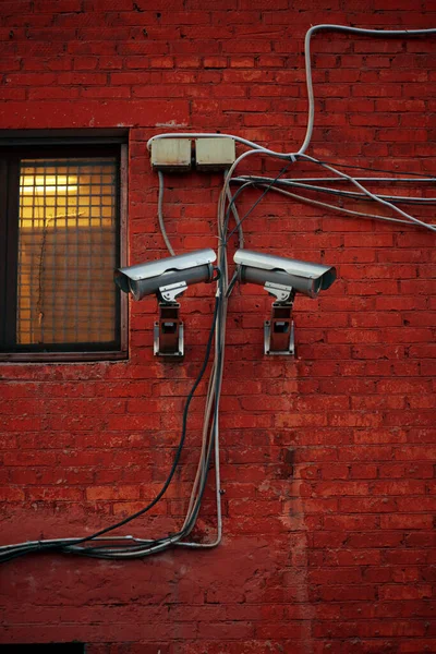 Zwei Metallische Überwachungskameras Roter Backsteinwand Mit Vergittertem Fenster Stromkabel Der — Stockfoto