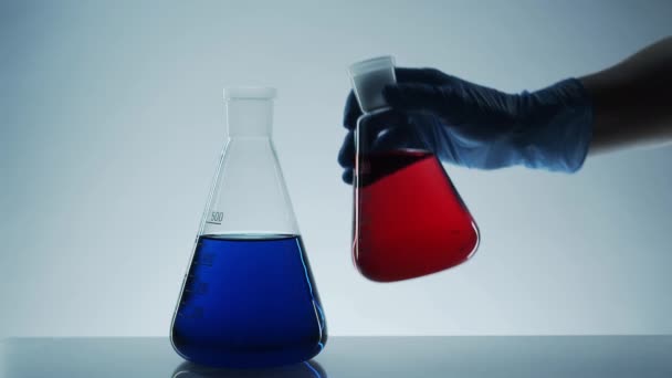 玻璃实验室的瓶子里装满了液体 实验室研究 天然化妆品 香水的生产 交医疗手套 在实验室里传送和混合不同的液体 — 图库视频影像