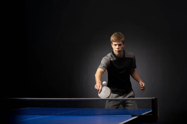 黒を背景にテニスをする若い男の肖像 — ストック写真