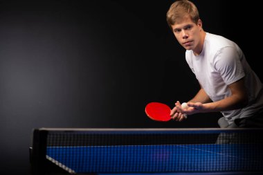 Siyah arka planda tenis oynayan genç adamın portresi. Servis tablosu onluk oynatıcı