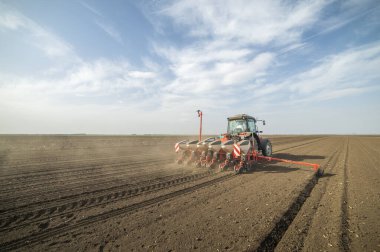 Traktör tohumu olan çiftçi - ilkbaharda tarım tarlalarına ekin ekiyor.