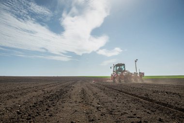 Traktör tohumu olan çiftçi - ilkbaharda tarım tarlalarına ekin ekiyor.