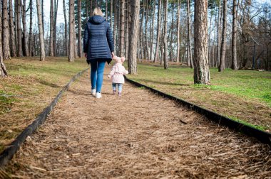 Anne ve çocuk ormanda kırsal yolda yürüyorlar.